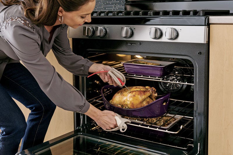 Woman inserting a temperature probe from a Trail Appliances oven into a Thanksgiving turkey.